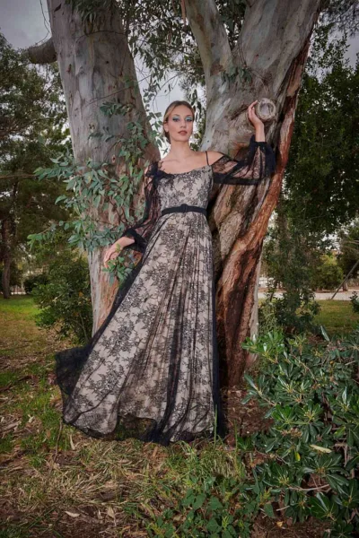 Estelle Dress Black by JULYTWO - Fine Chantilly lace with a plisse soleil skirt, off-the-shoulder top, wide sleeves, 3D lace rose brooch, and leather belt.
